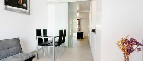 Un moderno vestíbulo de hotel con un sofá, zona de comedor y un jarrón de flores secas.