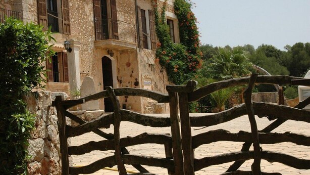 A stone building with a balcony, a wooden gate, and a sign that reads "20 LUNA". - Son Sama (Llucmajor)