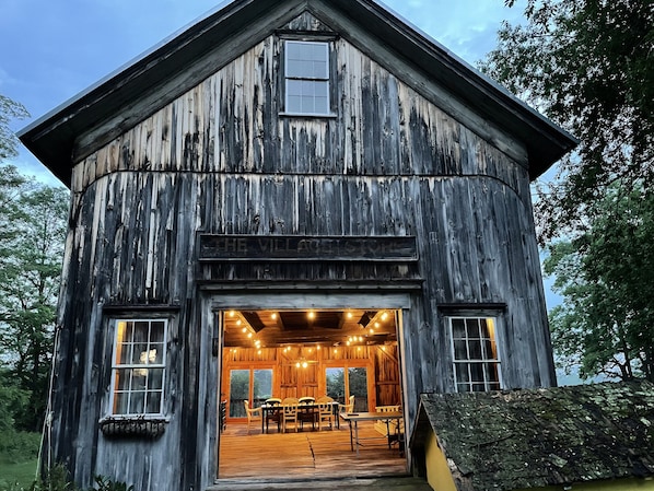 A rustic wooden building with a large open porch, wooden furniture, and a sign reading "The Village Store".