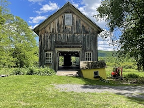 A rustic wooden building with a porch and a small adjacent structure.