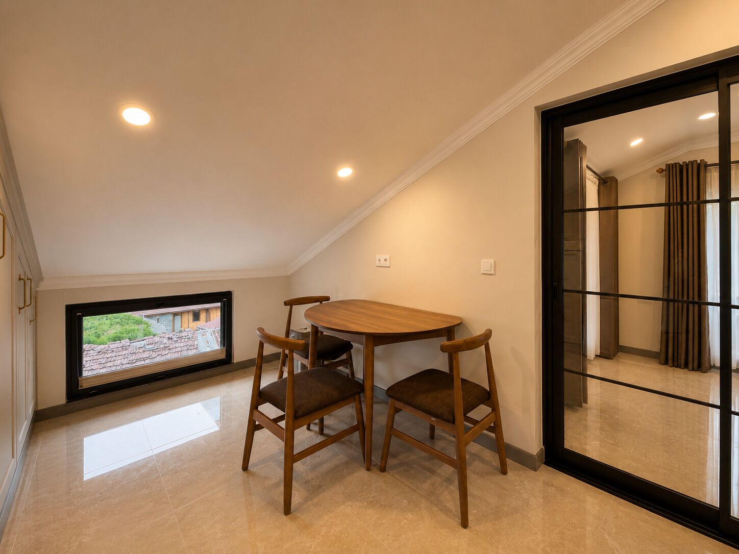 Una habitación con una mesa de comedor y sillas de madera, un televisor y una puerta corredera que da a otra habitación.