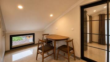 Una habitación con una mesa de comedor y sillas de madera, un televisor y una puerta corredera que da a otra habitación.