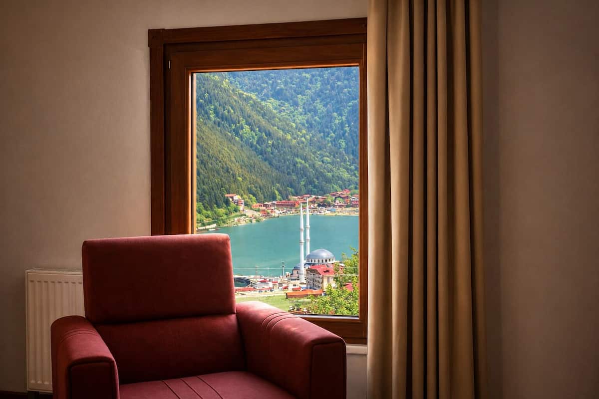 A room with a red chair, a view of a lake, and a mountain.