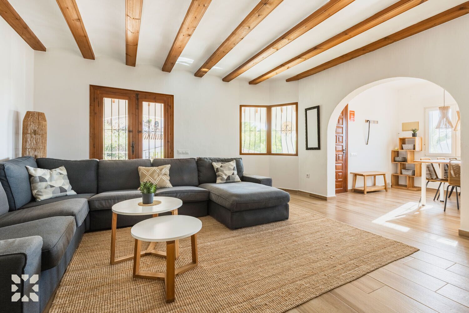 A modern living room with a sectional sofa, two round coffee tables, and a large rug.