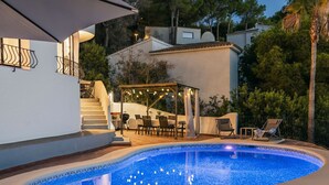 Ein Schwimmbecken mit einer Pergola und einer Sitzgelegenheit im Freien.