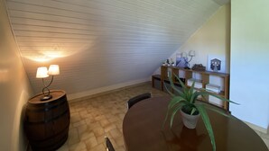 Ett mysigt rum med ett sluttande tak, en trätrumma, ett runt bord, en krukväxt och en hylla med dekorativa föremål.