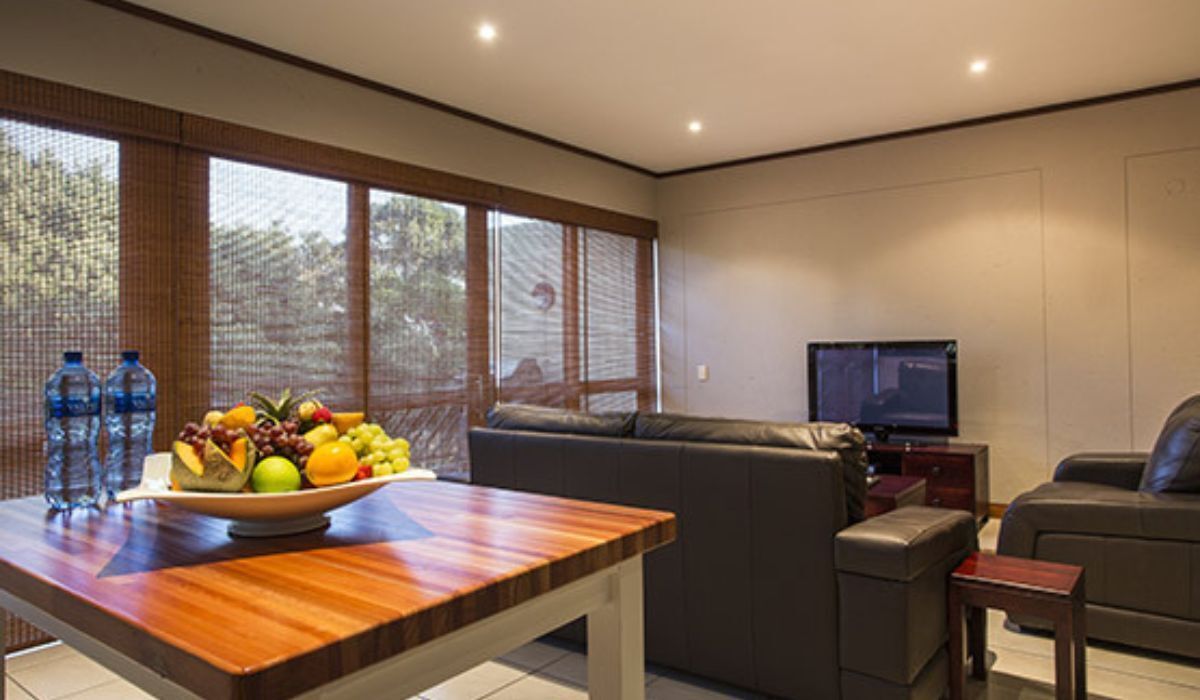 A modern living room with a wooden dining table, a sofa, and a television.