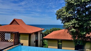 Un resort con piscina, vista al mar y un edificio de techo con tejas rojas.
