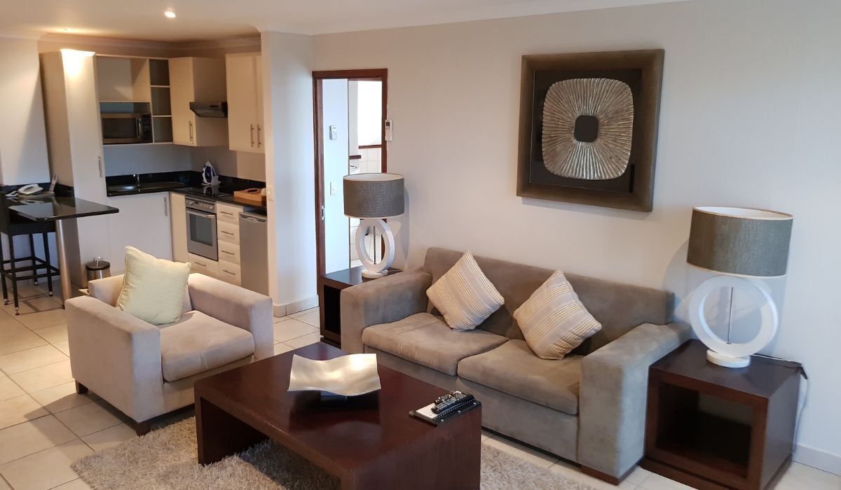 A modern living room with a sofa, coffee table, and a small kitchen area with a bar counter.
