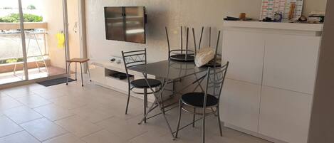 Une cuisine moderne avec une table et des chaises, un téléviseur fixé au mur et un calendrier posé sur le comptoir.