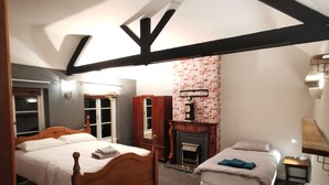 Un dormitorio con una cama de madera, una cama más pequeña, una chimenea y una mesita de noche.