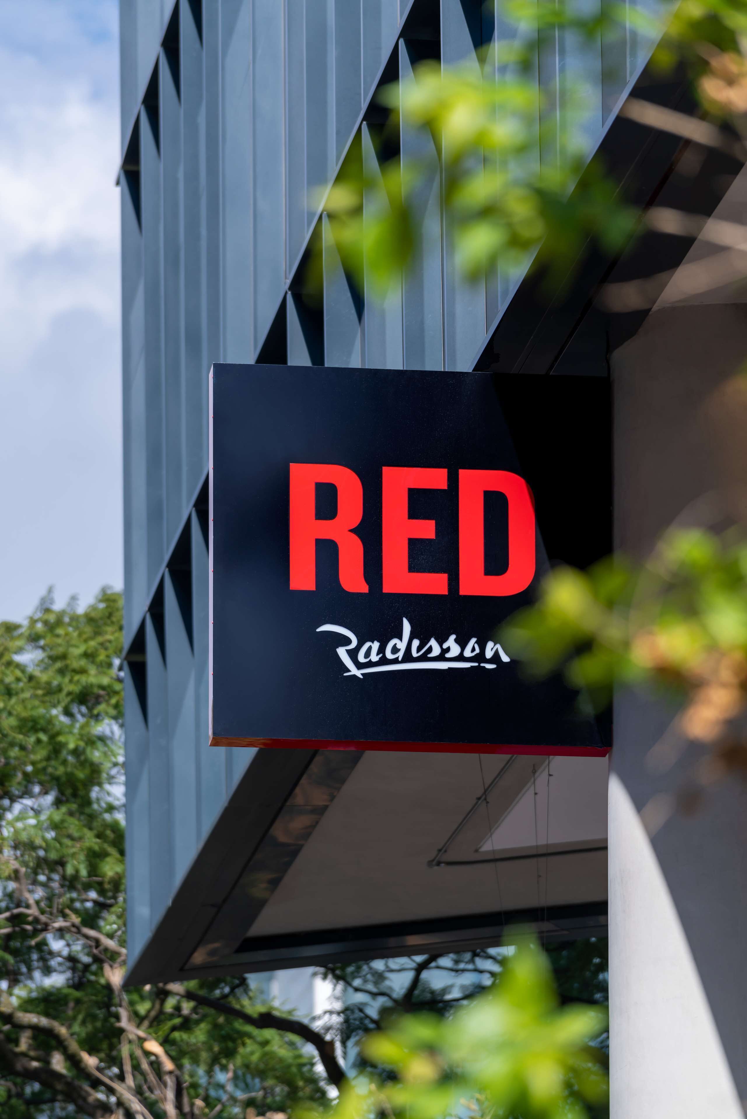 A sign with the word "RED" and the name "Radisson" on a building facade.