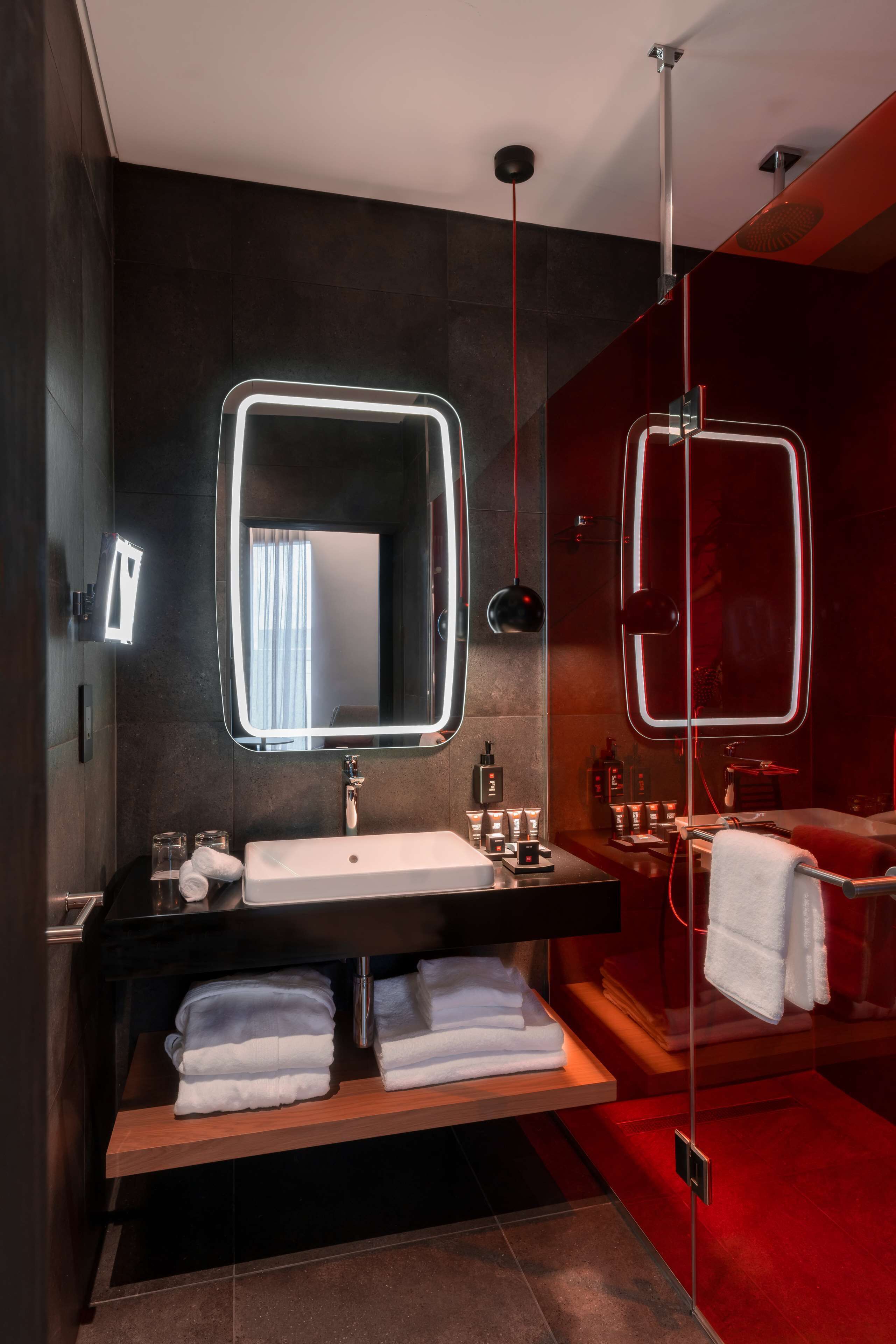 A modern bathroom with a large mirror, a sink, and a shower area.