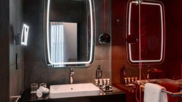 A modern bathroom with a large mirror, a sink, and a shower area.