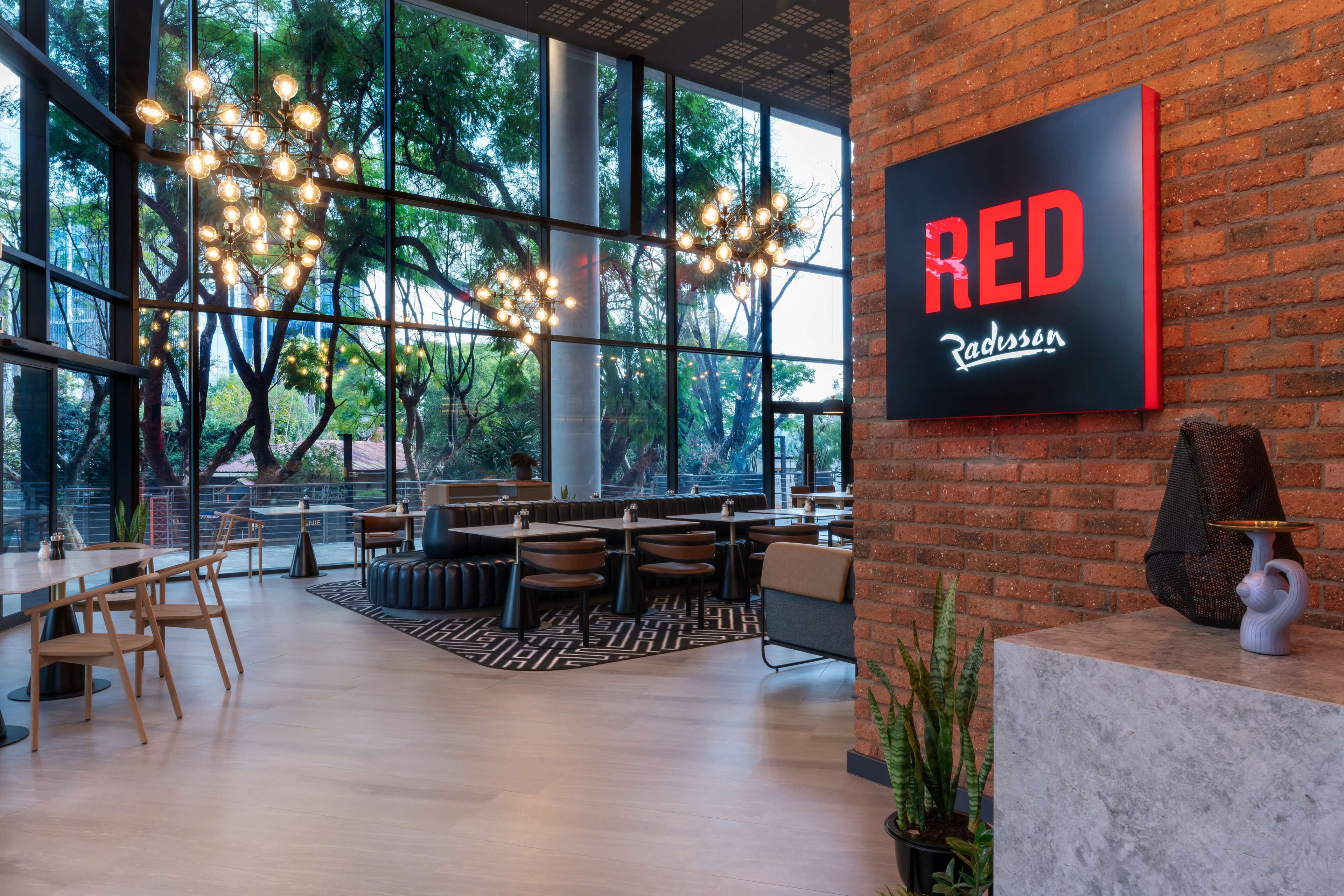 A spacious indoor area with large windows, a modern chandelier, and a prominent RED Radisson sign.