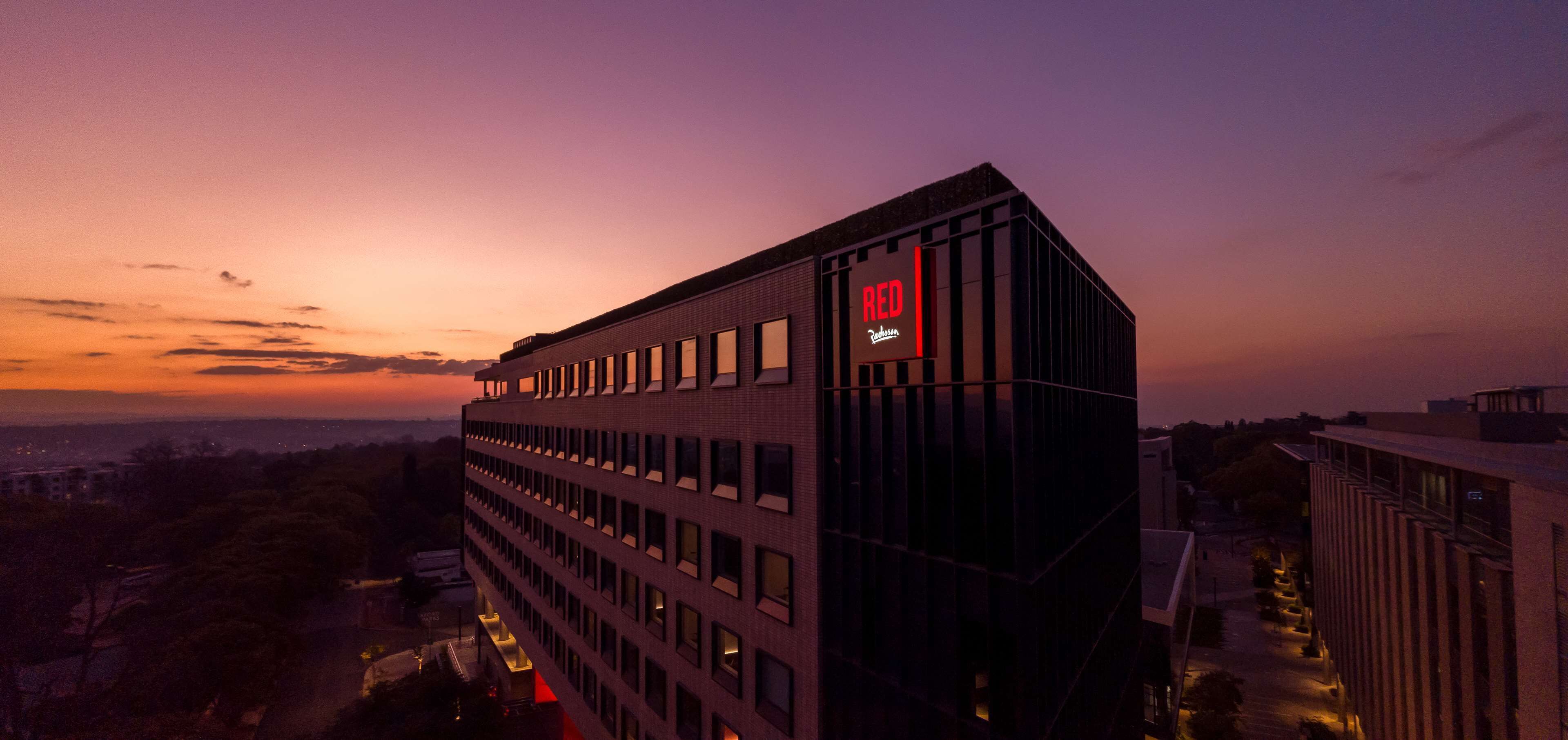 A modern building with a prominent 'RED' sign, multiple windows, and a flat roof.