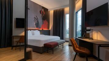 Una habitación de hotel moderna con una cama grande, un escritorio, una silla y un televisor.