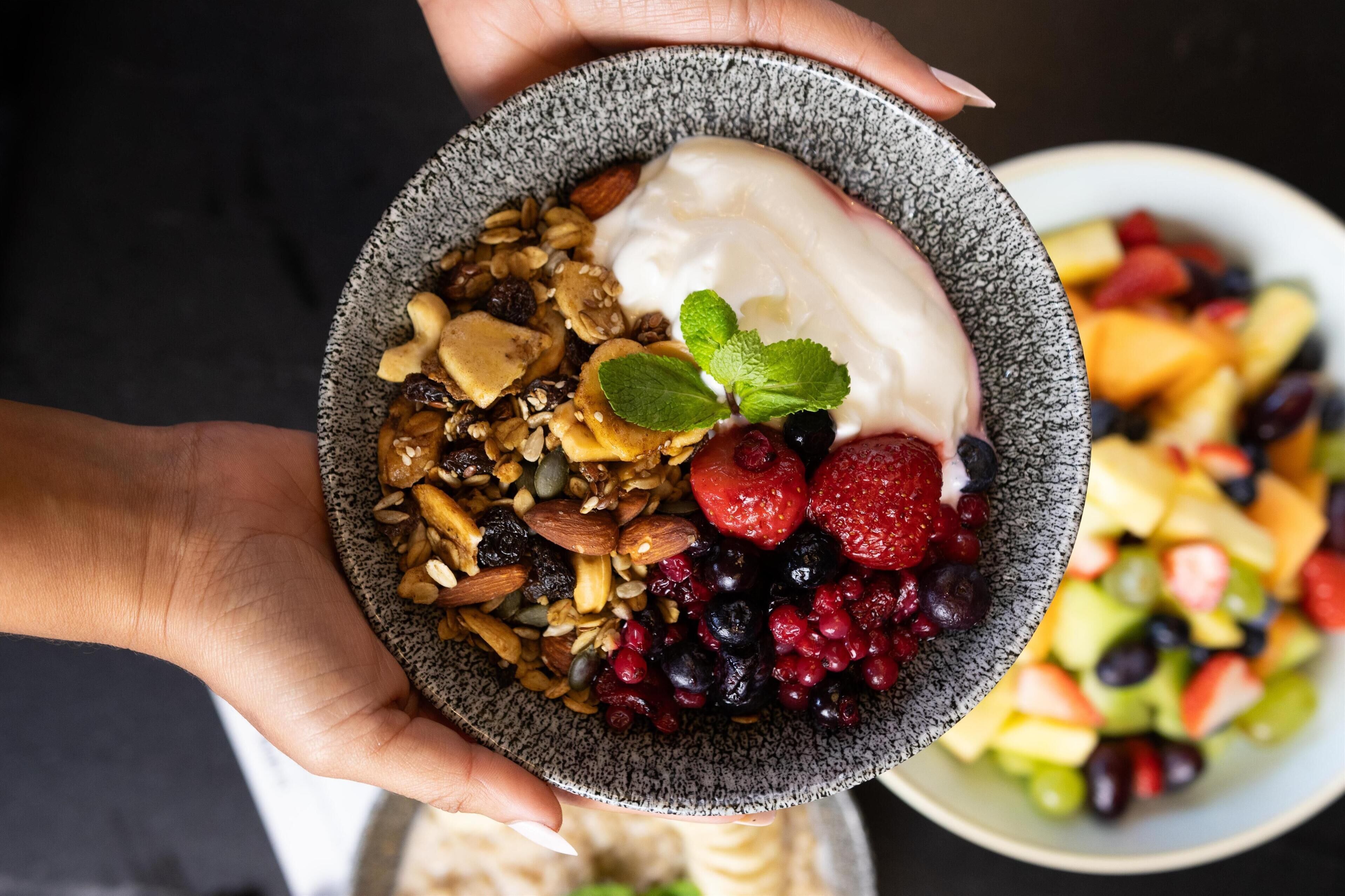A bowl of yogurt with granola, nuts, and berries.