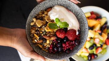 A bowl of yogurt with granola, nuts, and berries.