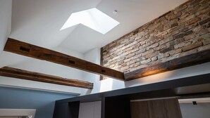 A room with exposed wooden beams, a sloped ceiling, and a brick wall. - Oldtown Studios by dasPaul (Nuremberg)