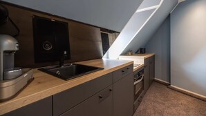 A modern kitchen with a built-in sink, dark cabinetry, and a wooden countertop. - Oldtown Studios by dasPaul (Nuremberg)