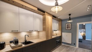 A modern kitchen with wooden cabinets, a built-in oven, and a coffee maker. - Oldtown Studios by dasPaul (Nuremberg)