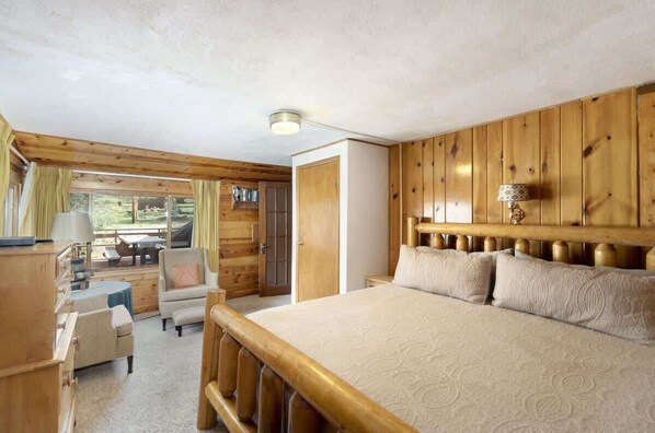 Ein gemütliches Schlafzimmer mit einem großen Bett, einem Holzkopfteil und Blick ins Freie.