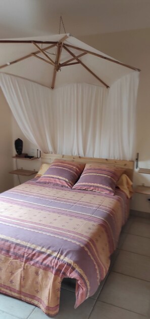 Un lit à baldaquin, une table de chevet et une commode.