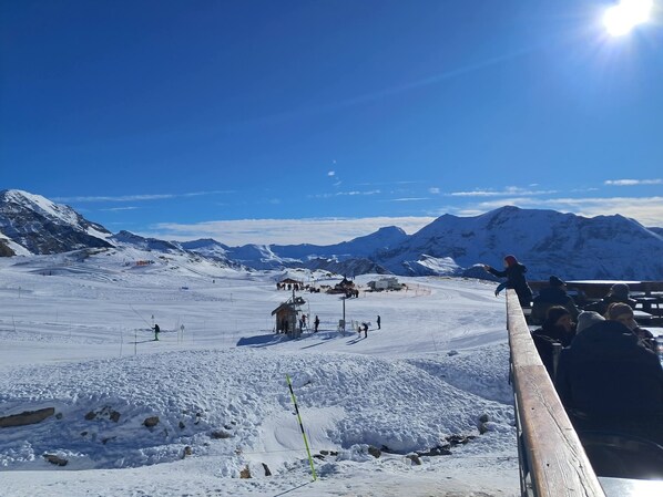 A snowy mountain landscape with a ski lift and a wooden viewing platform.
