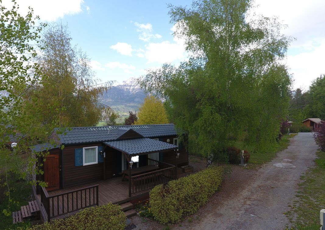 A wooden cabin with a porch, surrounded by trees and a mountain view.