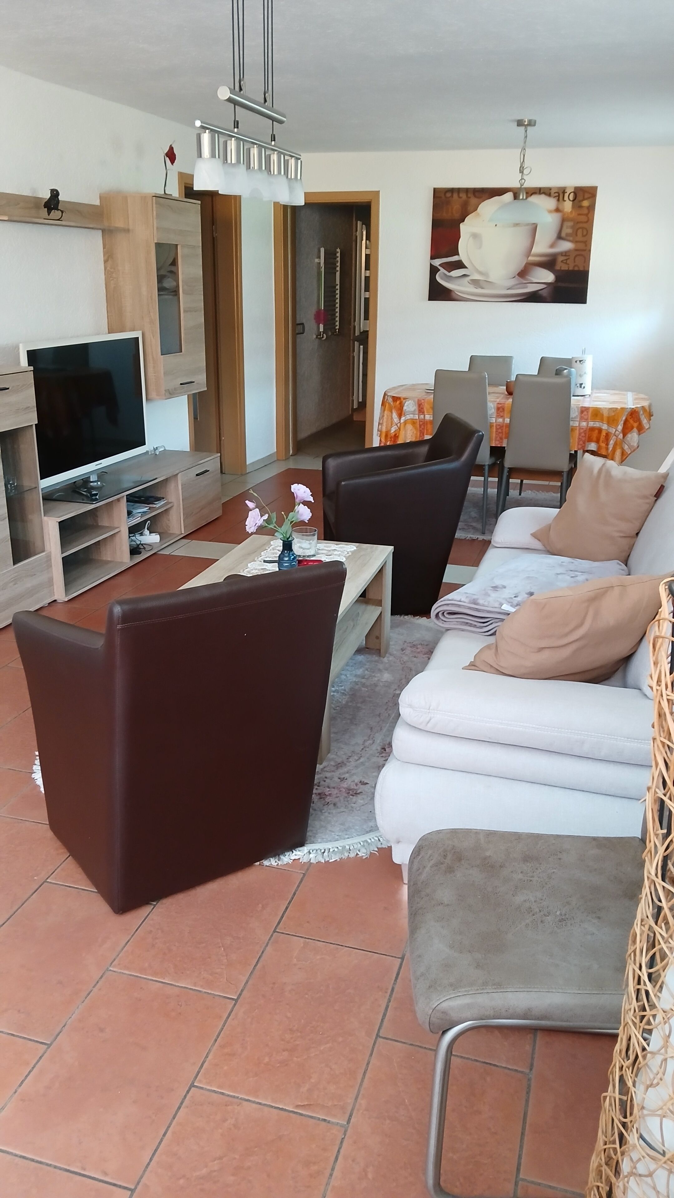 En moderne stue med sofa, sofabord, fjernsyn og spiseområde.