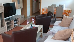 Una sala de estar moderna con sofá, mesa de centro, televisor y comedor.