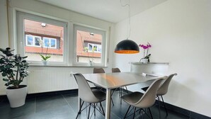 A dining area with a table and chairs, a potted plant, and a window with a view of buildings. - Superior 3 room Apartment Cathedral View (Ulm)