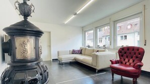 A modern living room with a large black stove, a white sofa, and a red armchair. - Superior 3 room Apartment Cathedral View (Ulm)