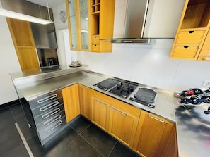 Une cuisine moderne dotée d’appareils électroménagers en acier inoxydable, de meubles en bois et d’un four encastré.