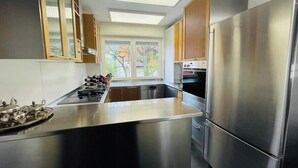 A modern kitchen with stainless steel appliances, a central island, and a view of the outside. - Superior 3 room Apartment Cathedral View (Ulm)