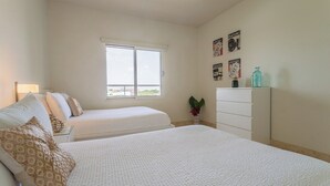 Een slaapkamer met twee bedden, een dressoir, een raam en wanddecoraties.