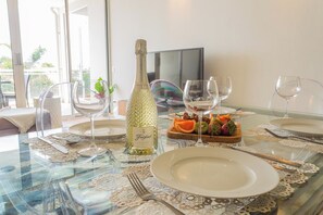 A dining table set with a bottle of champagne, fruit, and wine glasses. - 2BR Condo w/ Balcony & Pool near Eagle Beach (Eagle Beach)