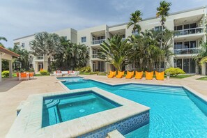 Un hotel con piscina, mobiliario exterior y palmeras.