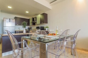 A modern kitchen with a glass dining table, clear chairs, and stainless steel appliances. - Pool Access! 2BR Condo w Balcony near Eagle Beach (Eagle Beach)