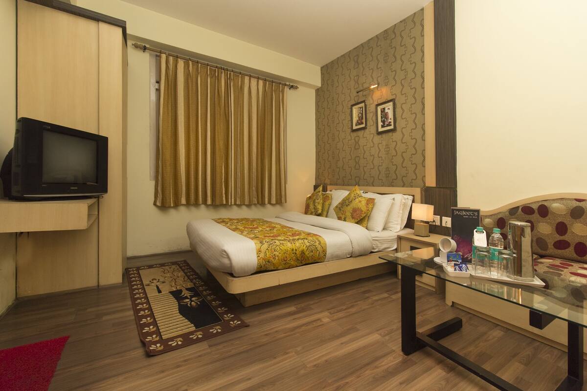 Une chambre d’hôtel avec un lit, une télévision, une table basse en verre et un canapé.
