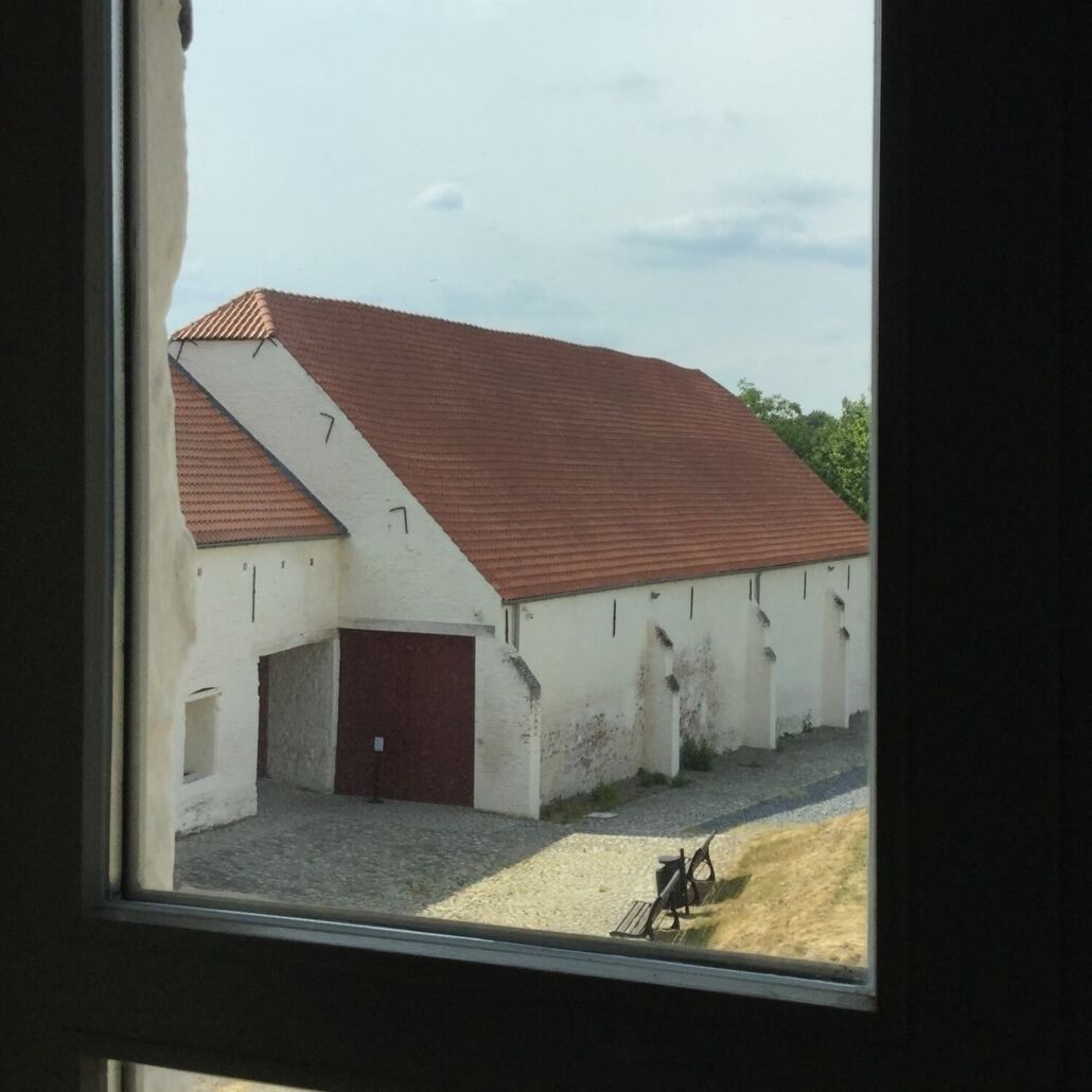 A building with a red roof and white walls, viewed through a window.
