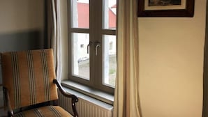 Una habitación con ventana, radiador y una silla.