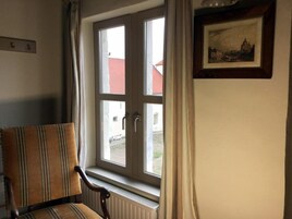 Una habitación con ventana, radiador y una silla.