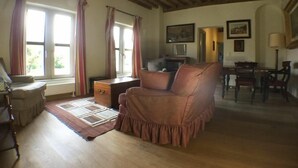 Una sala de estar acogedora con techo de madera, un sofá marrón, un aparador de madera y una zona de comedor con sillas y una mesa.