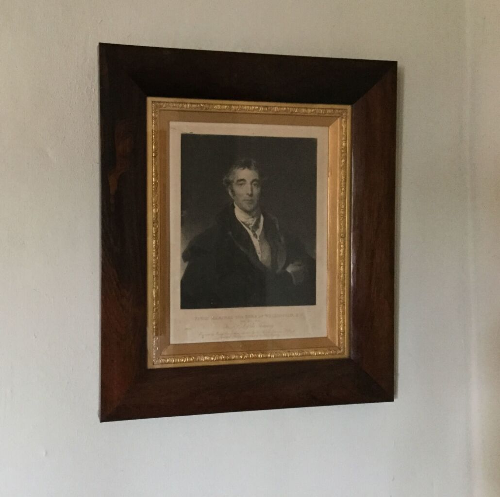 A framed portrait of a man in formal attire, mounted on a wall.