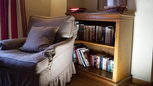 Una habitación con un sillón de cuero, una estantería de madera llena de libros y un cuadro en la pared.
