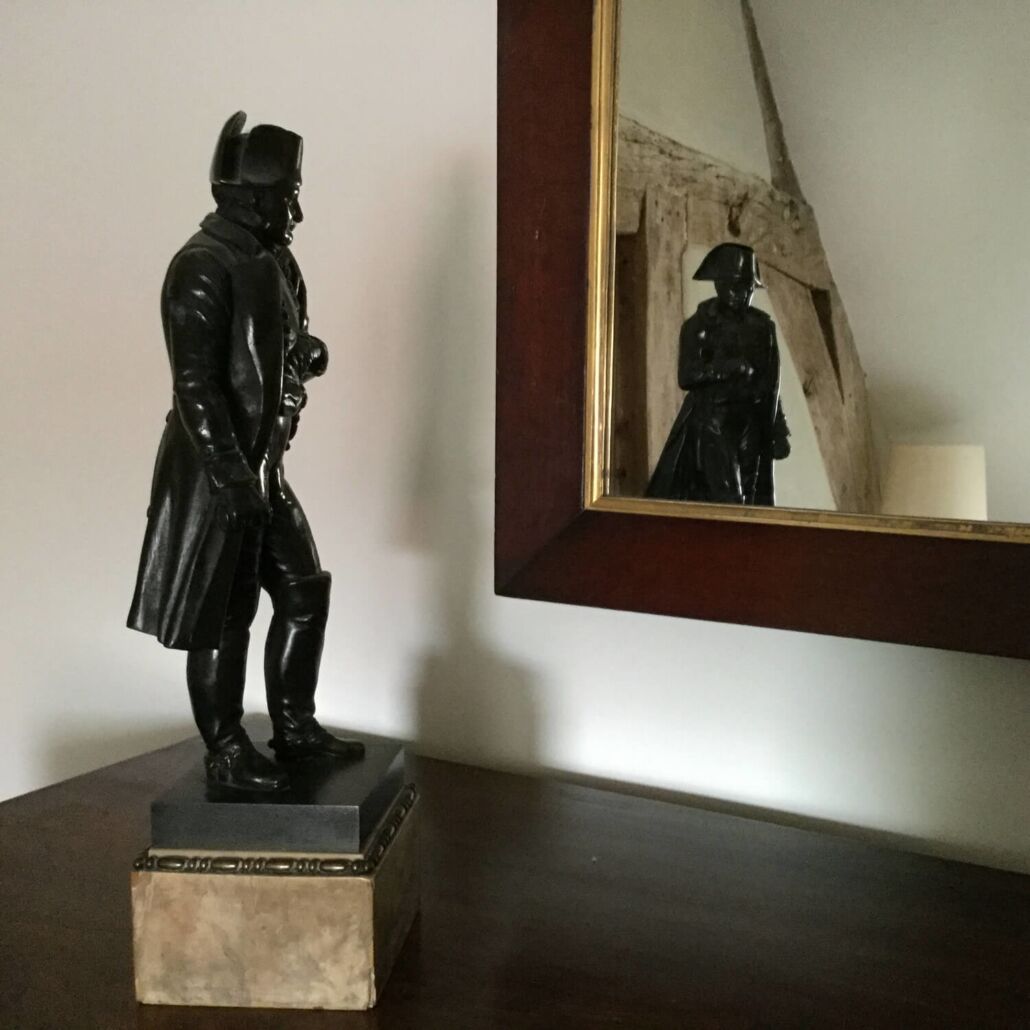 En statue på en sokkel ved siden af et spejl, der viser statuen.
