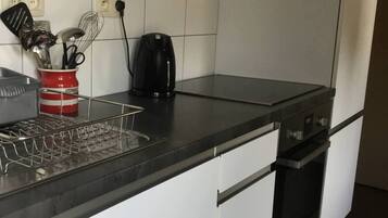 A kitchen with a black countertop, a coffee maker, and a utensil holder.
