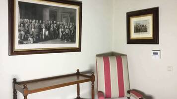 Um quarto com uma fotografia a preto e branco emoldurada, uma poltrona riscada e uma mesa de cabeceira de madeira.